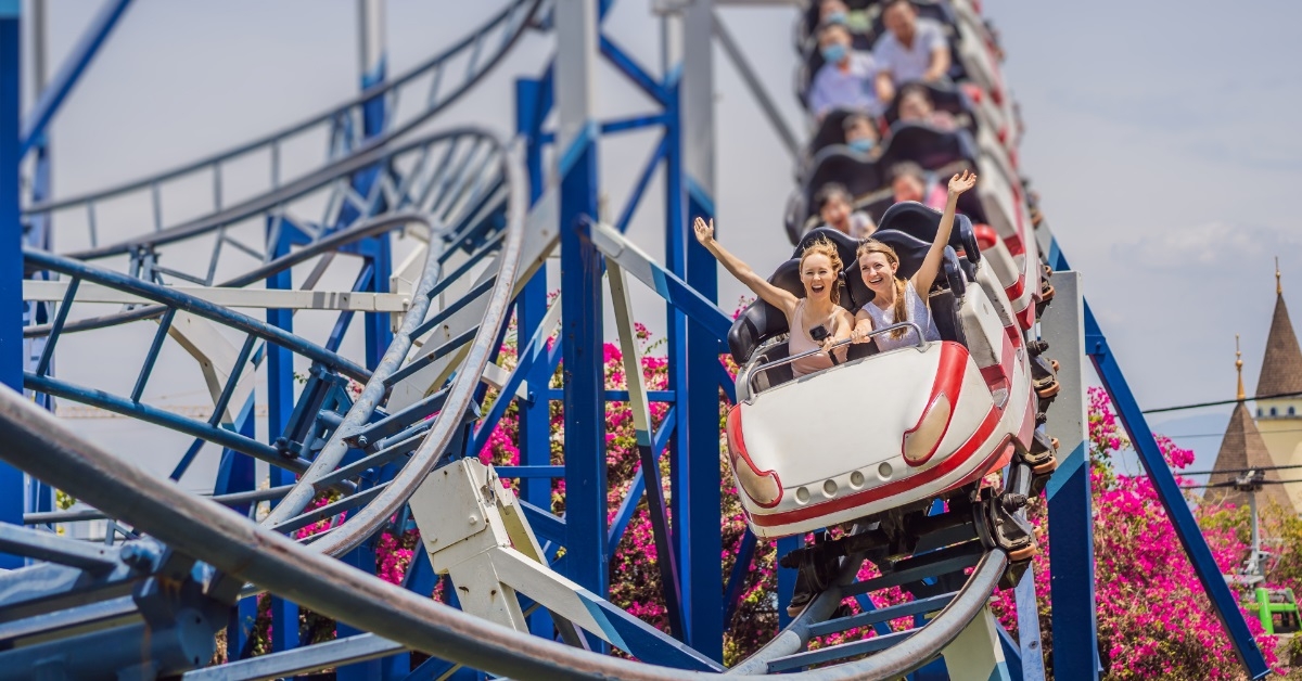 friends raising hands on roller coaster