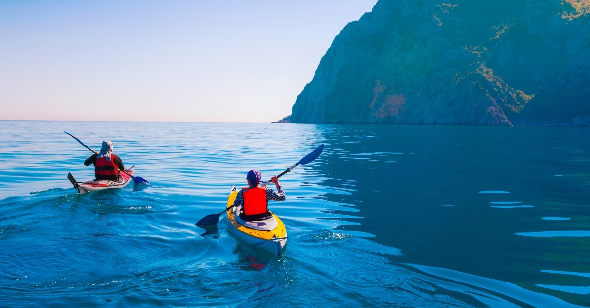 couple canoeing in ocean with mountains