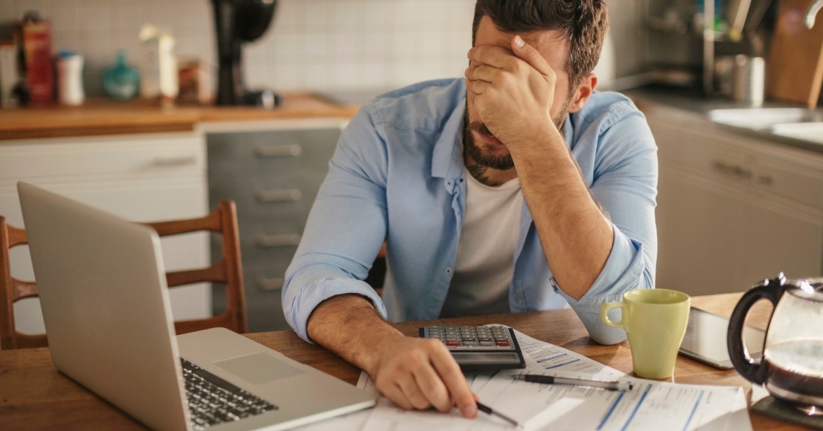 man frustrated at bills in kitchen