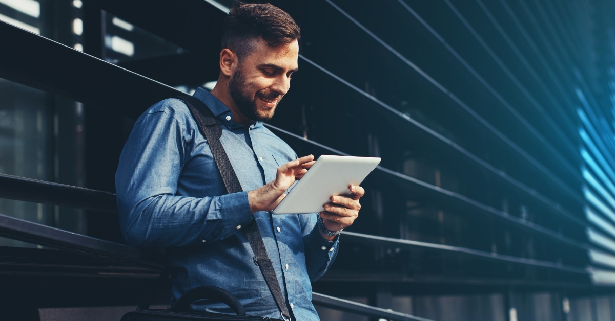 happy man using tablet outside office