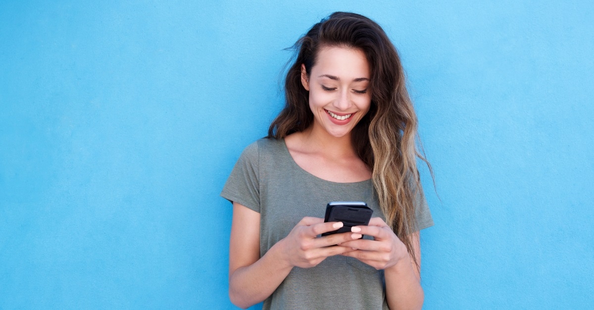 woman smiling while using smartphone