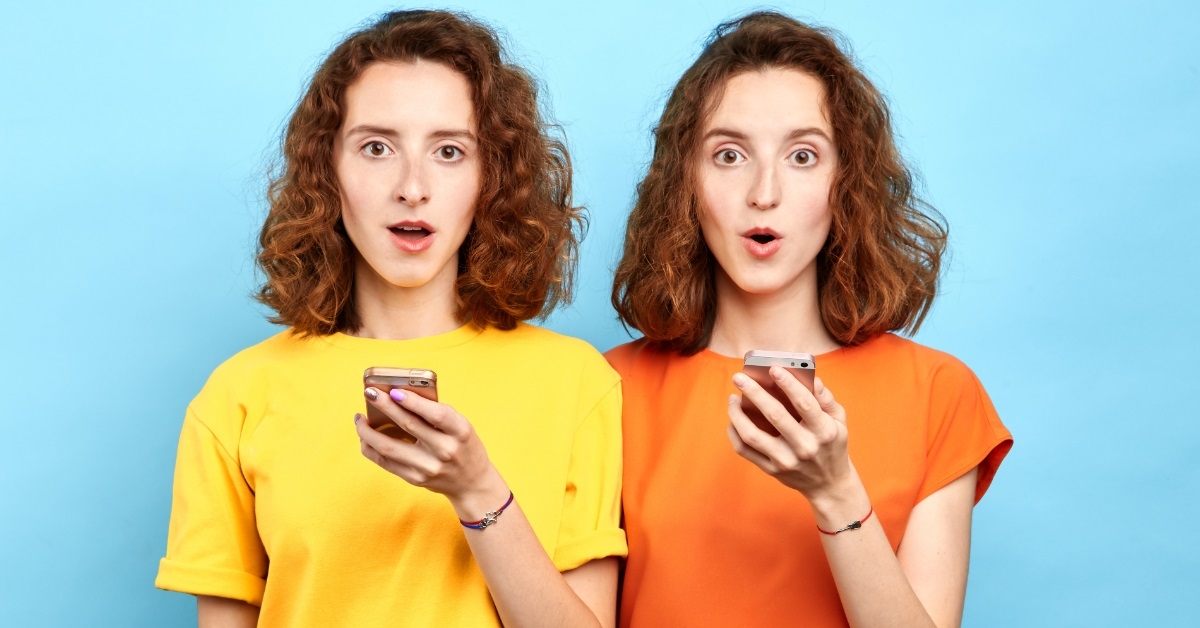 twins surprised while holding smartphone