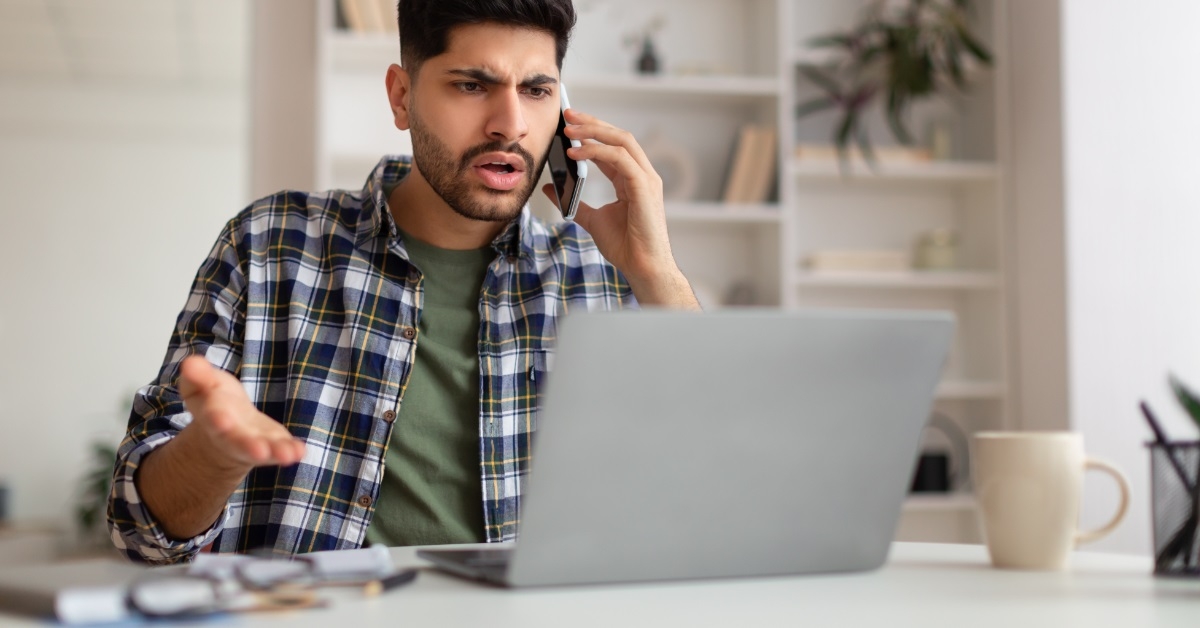 confused man on call using laptop