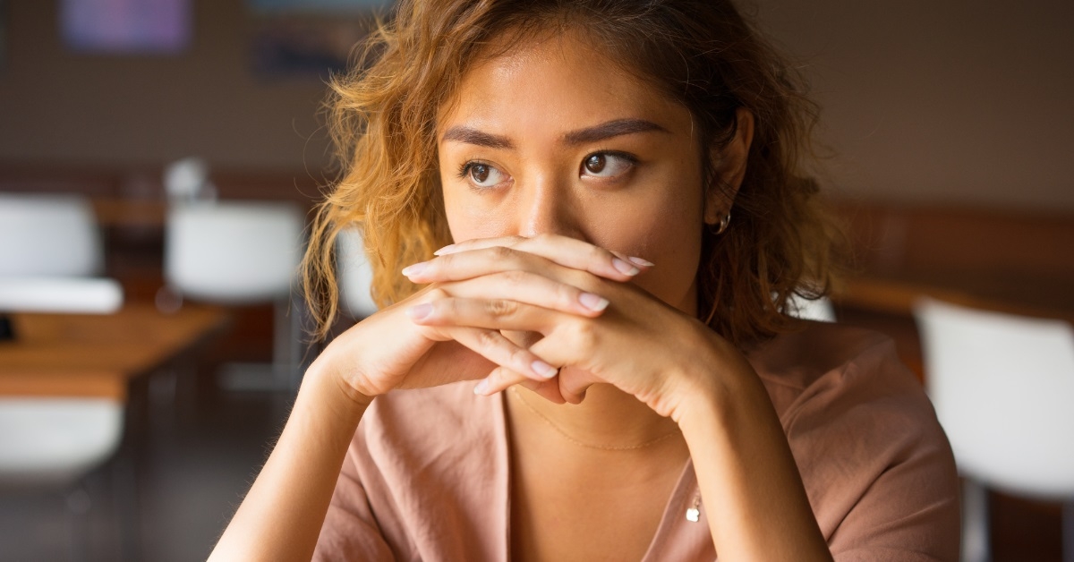 woman covering mouth with clasped hands