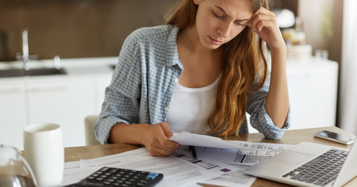 stressed woman reviewing bills in kitchen