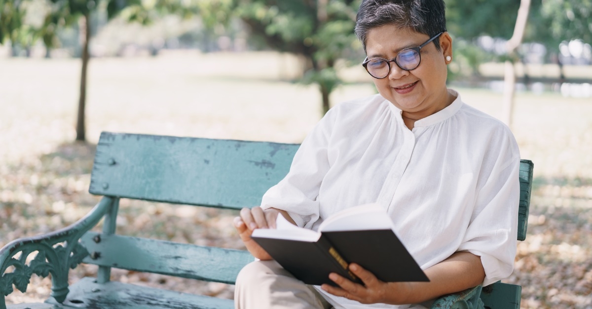 senior woman reading book outdoors