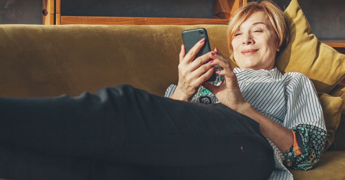 senior woman scrolling phone at home