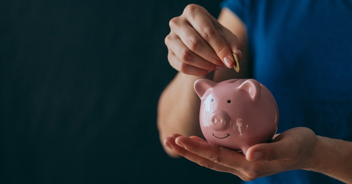 hands hold a pink piggy bank
