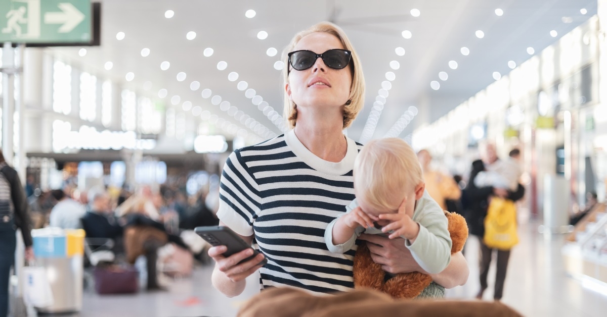 woman holding infant boy at airport