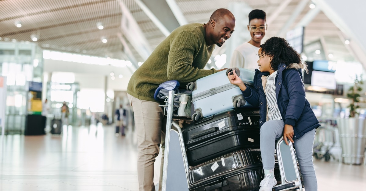family with luggage trolley at airport