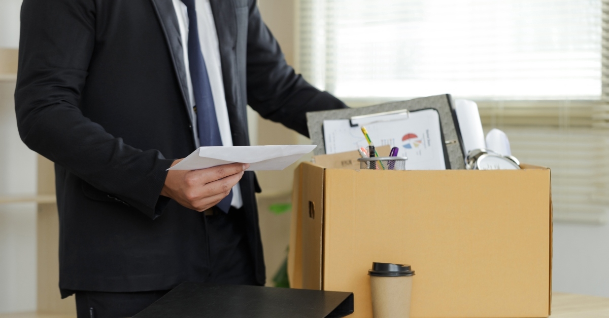 man holds box and resignation letter