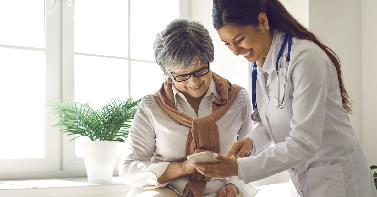 doctor showing smartphone to senior lady