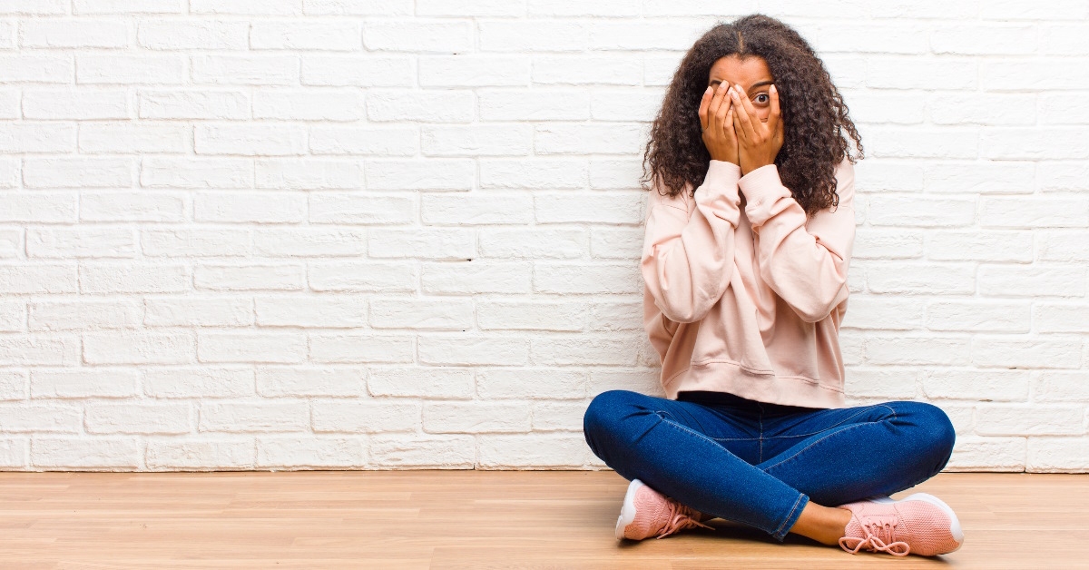 scared african american woman covering face