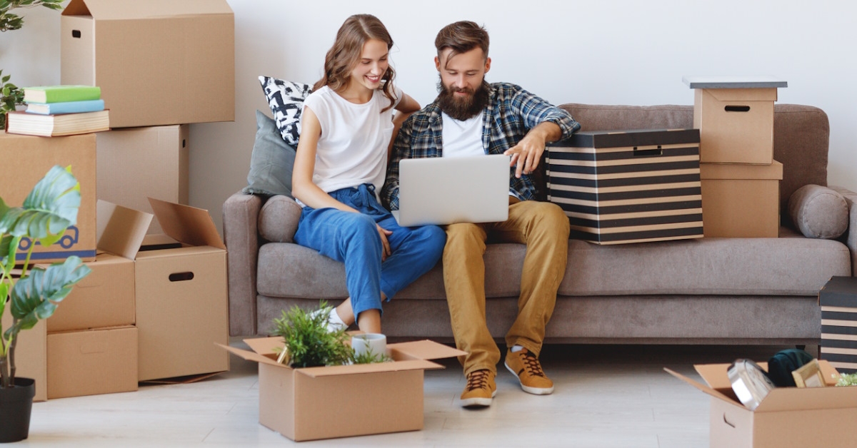 couple with moving boxes using laptop