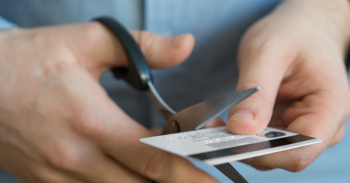 man cutting credit card with scissor