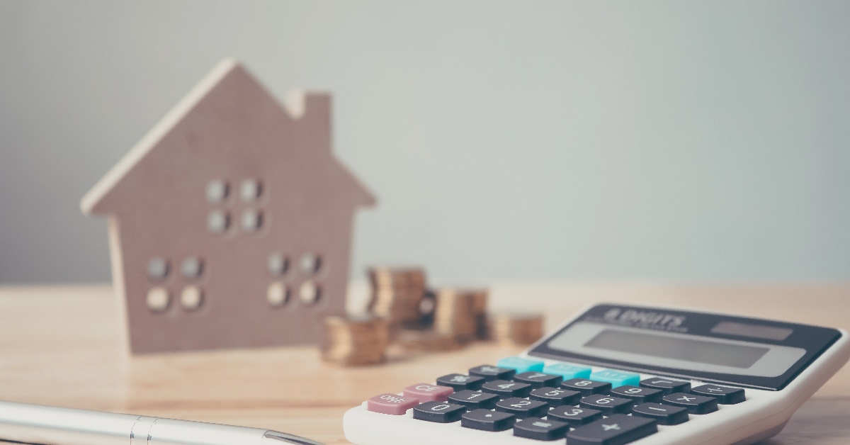 calculator besides pennies with house sculpture