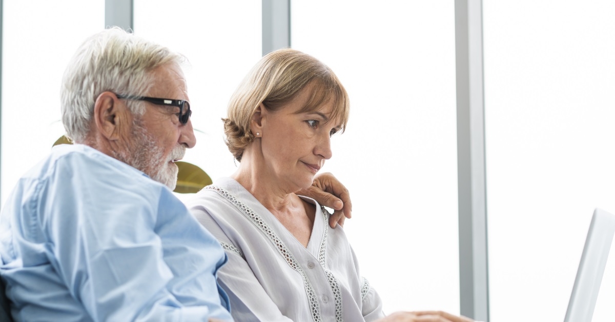 senior couple calculating bills on laptop