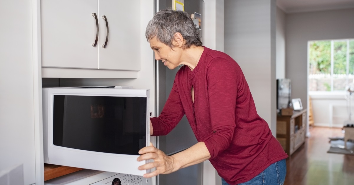 woman using microwave oven at home
