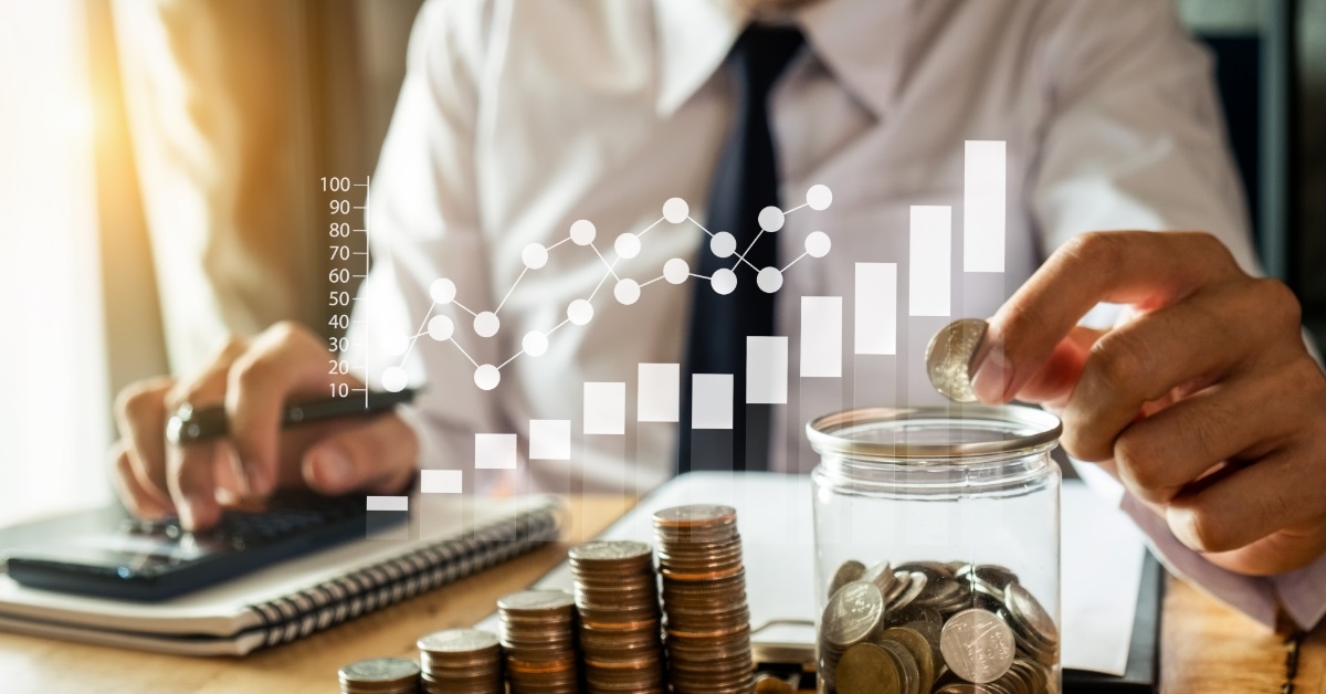 businessman saving pennies in glass jar