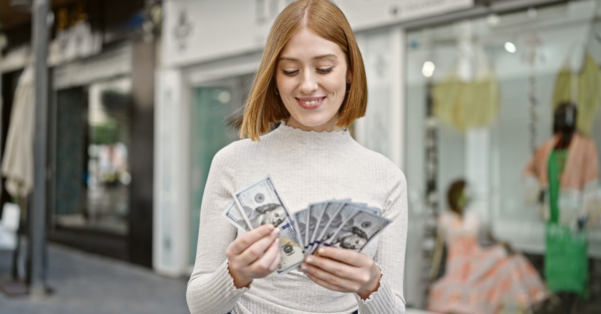 confident woman counting dollars on street