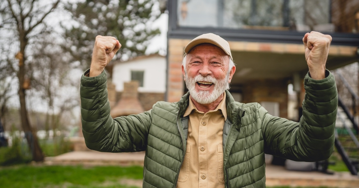 senior man cheering outside new house