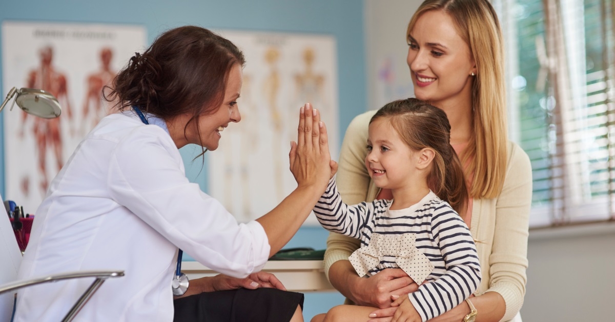 friendly female pediatrician cheering young girl
