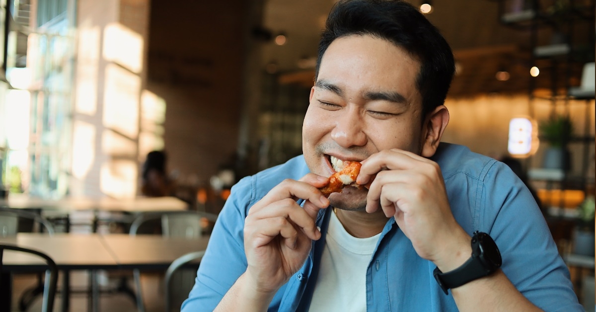 asian man having chicken wings 