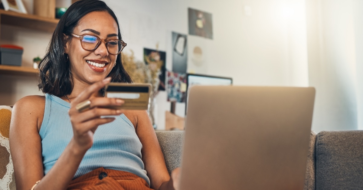 happy woman using card on laptop