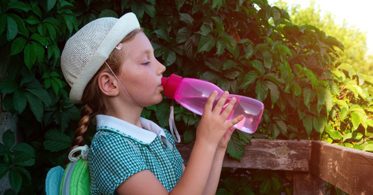 girl drinking water from pink bottle