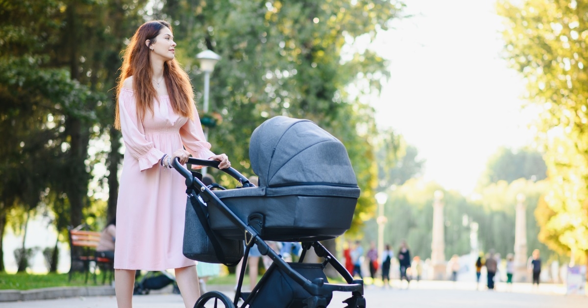 woman walking baby stroller in park