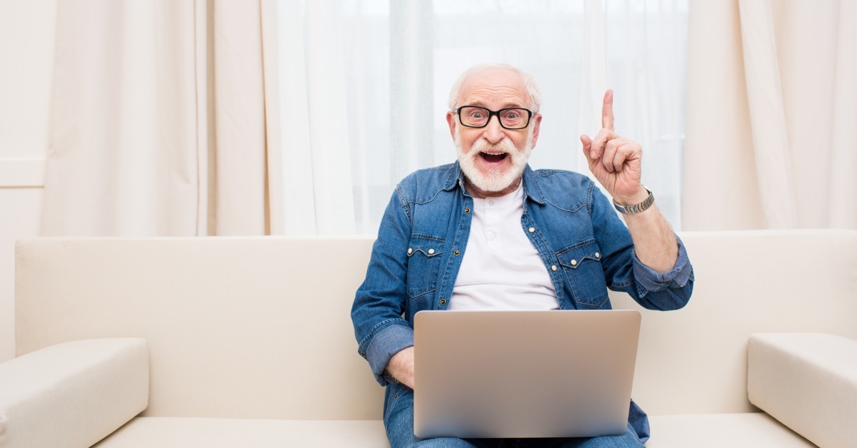 senior man cheering while using laptop