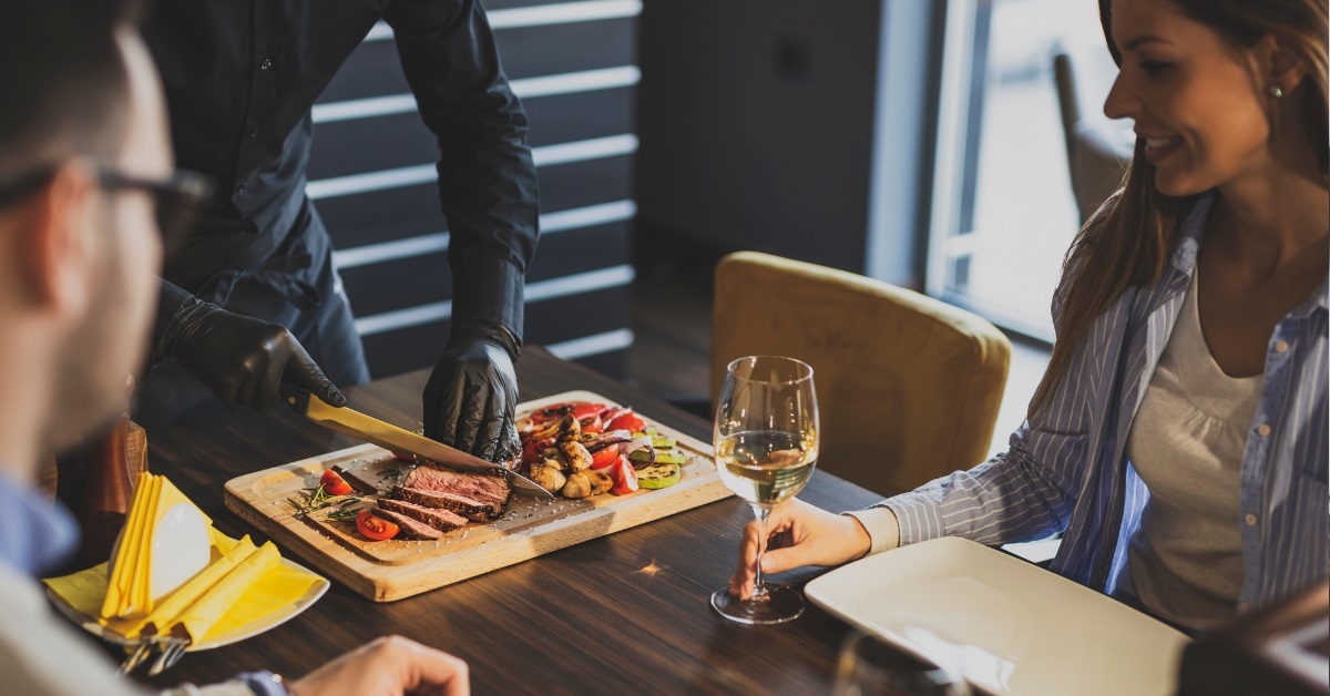 chef slicing beef steak for couple