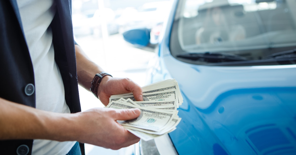 man counting money after selling car