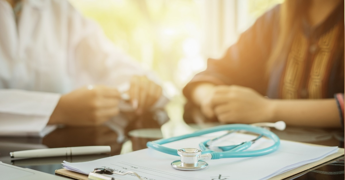stethoscope placed on a desk with a clipboard and laptop