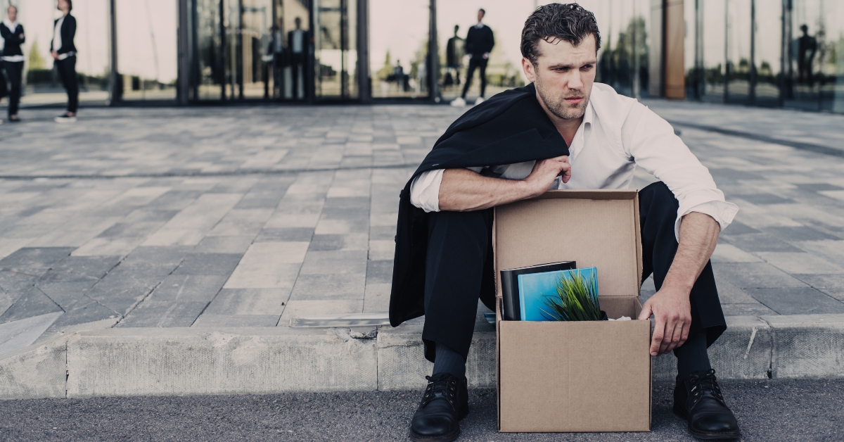 fired businessman sitting on street
