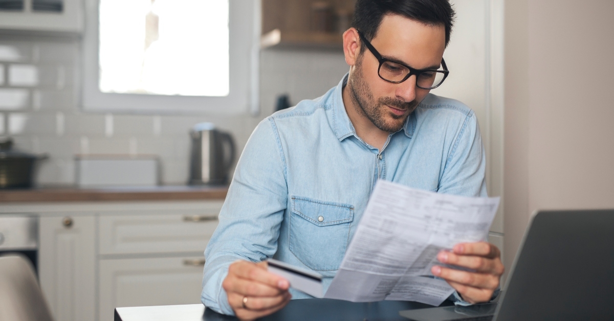 man holding credit card and paper