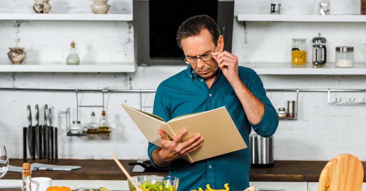 man using cookbook in kitchen
