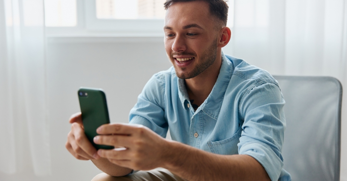 young man looks at phone screen