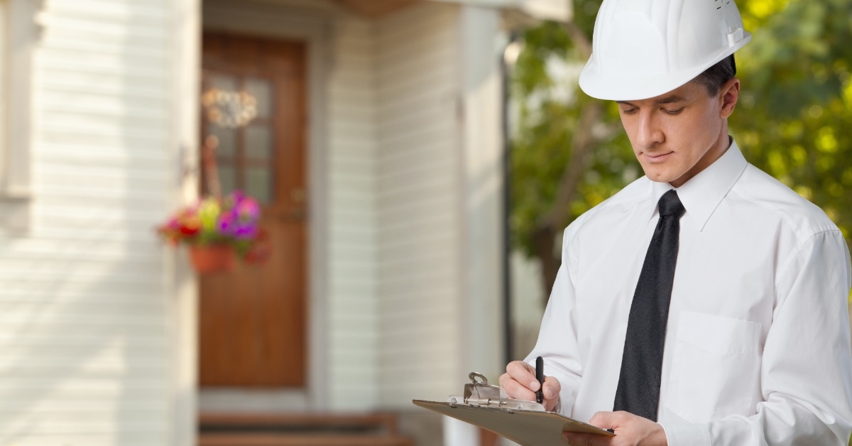 male engineer inspecting home with checklist