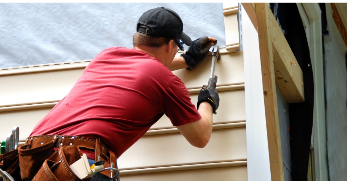 man hammering nail on exterior wall