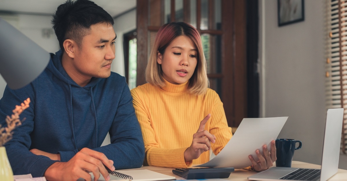 asian couple reviewing bills at home