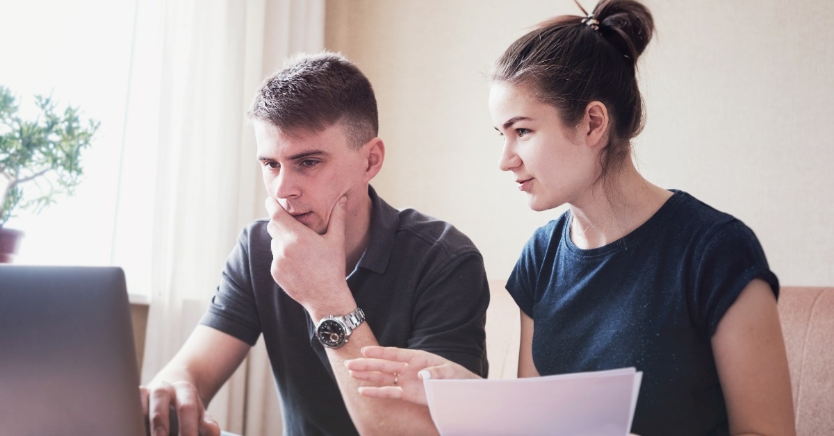 young couple reviewing bills using laptop