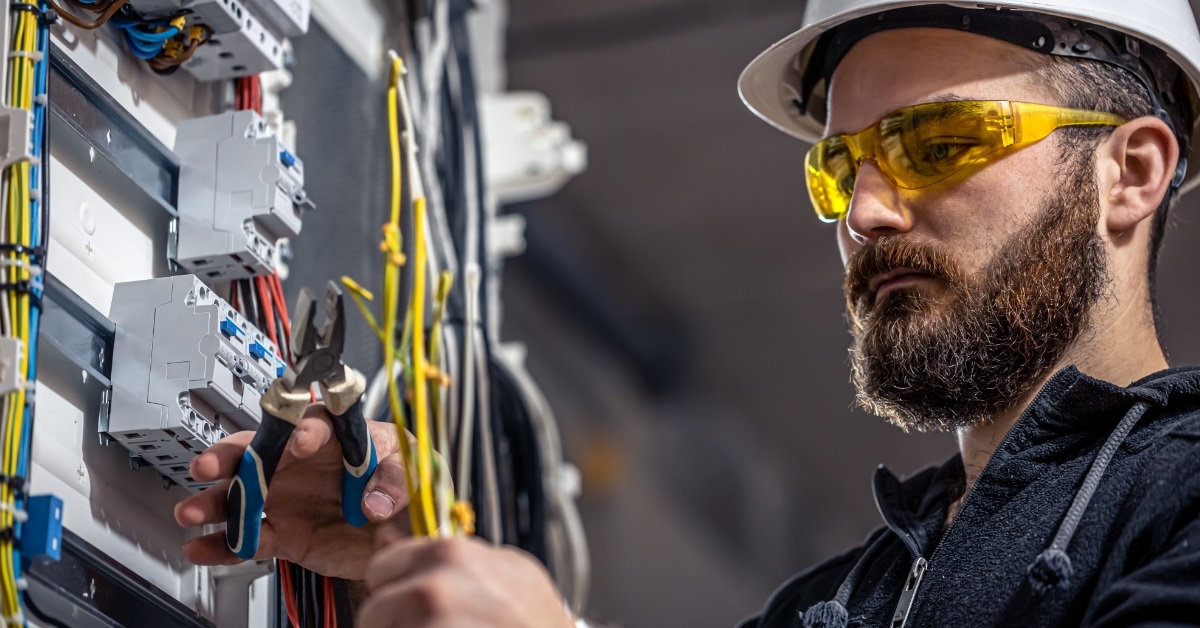 male electrician connecting cables in switchboard