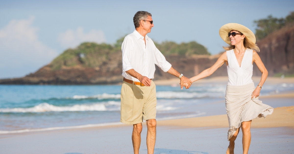 happy senior couple walking on beach
