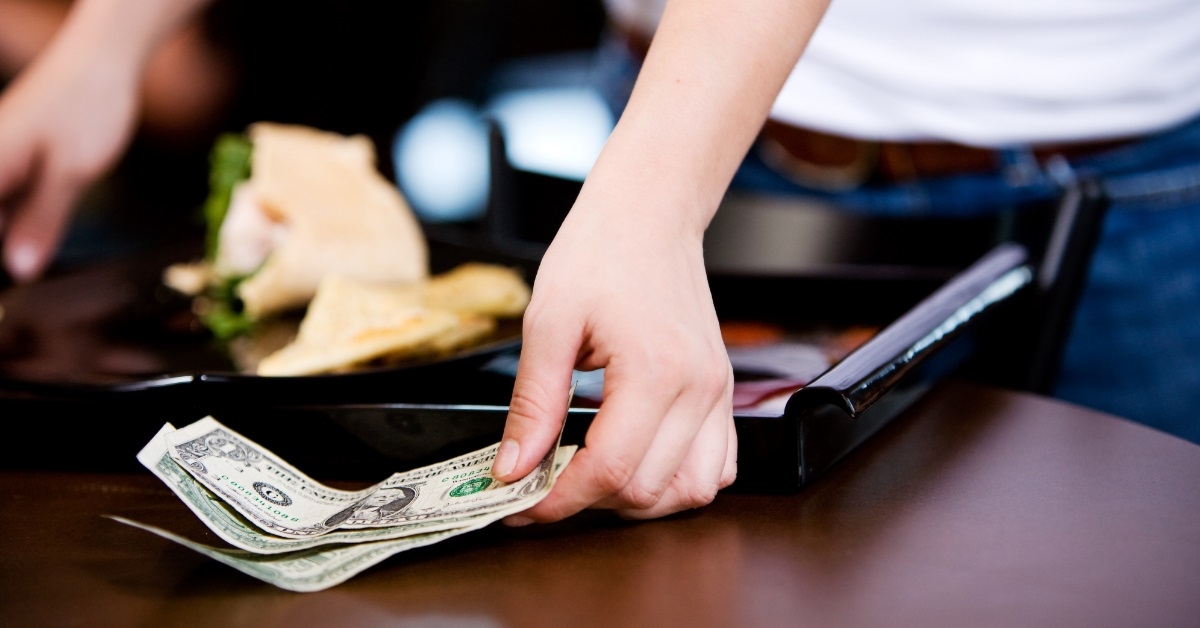 male server collecting tip from table