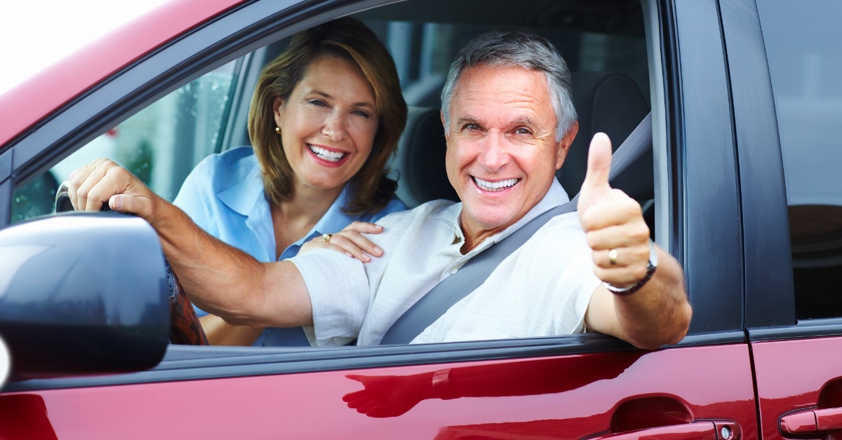 happy senior couple posing in car