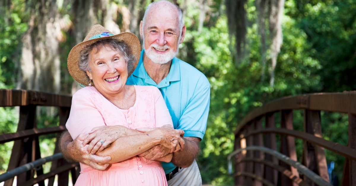 romantic senior couple hugging on bridge