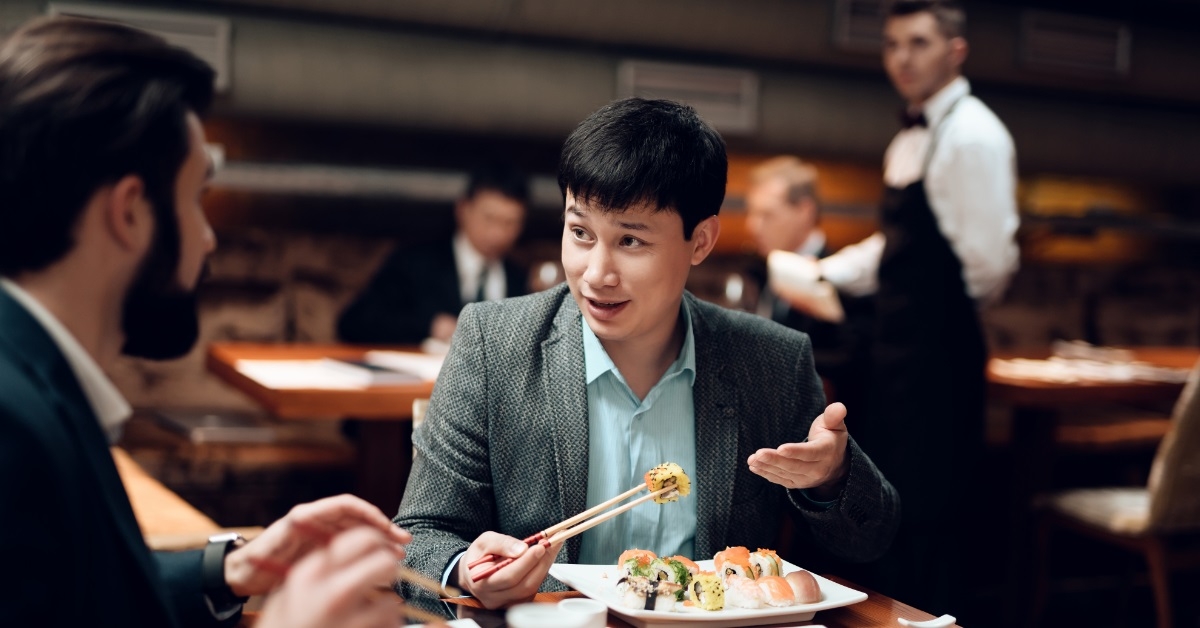 asian businessman eating sushi in restaurant