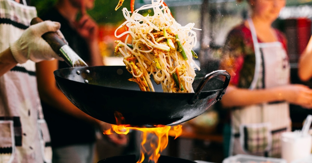 chef stirring noodles in outdoor restaurant