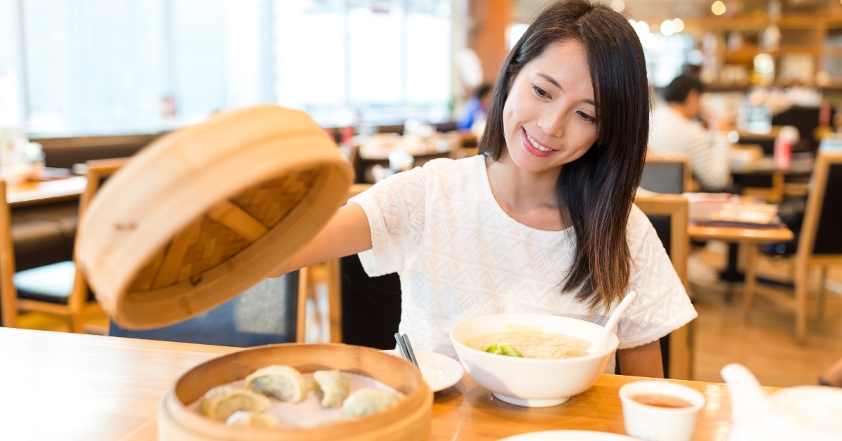 asian woman trying dumplings at restaurant
